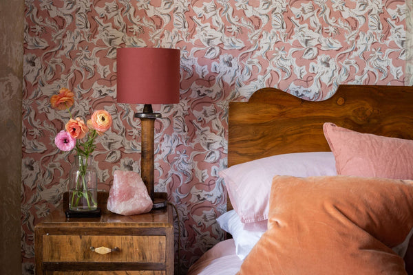 A wallpapered bedroom in dusty pink and terracotta — wooden headboard, soft linens, ranunculus in a glass — the domestic world of the brands featured in this Söstter spotlight.