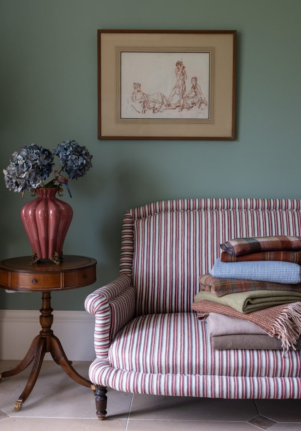 striped armchair with a side table and vase filled with blue flowers on Sostter