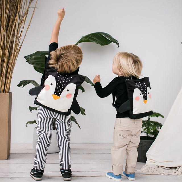Two young children wearing matching penguin backpacks from Baltic brands, featured on the Sostter marketplace.