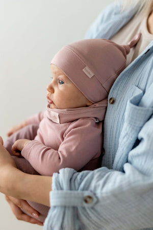 soft bamboo baby hat polly resting gently on a cozy blanket, showing its adjustable knot