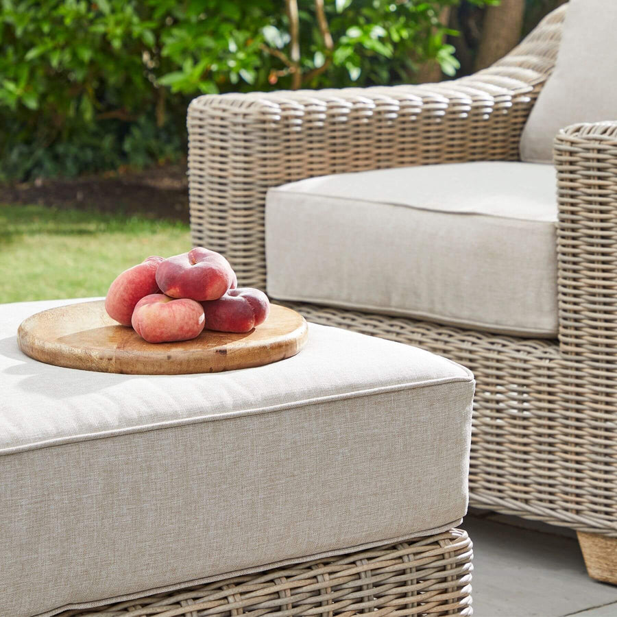 Beige HDPE wicker footstool with Olefin cushion, aluminum frame, and acacia wood feet for outdoor patio or garden. by Sostter at brixbailey.com