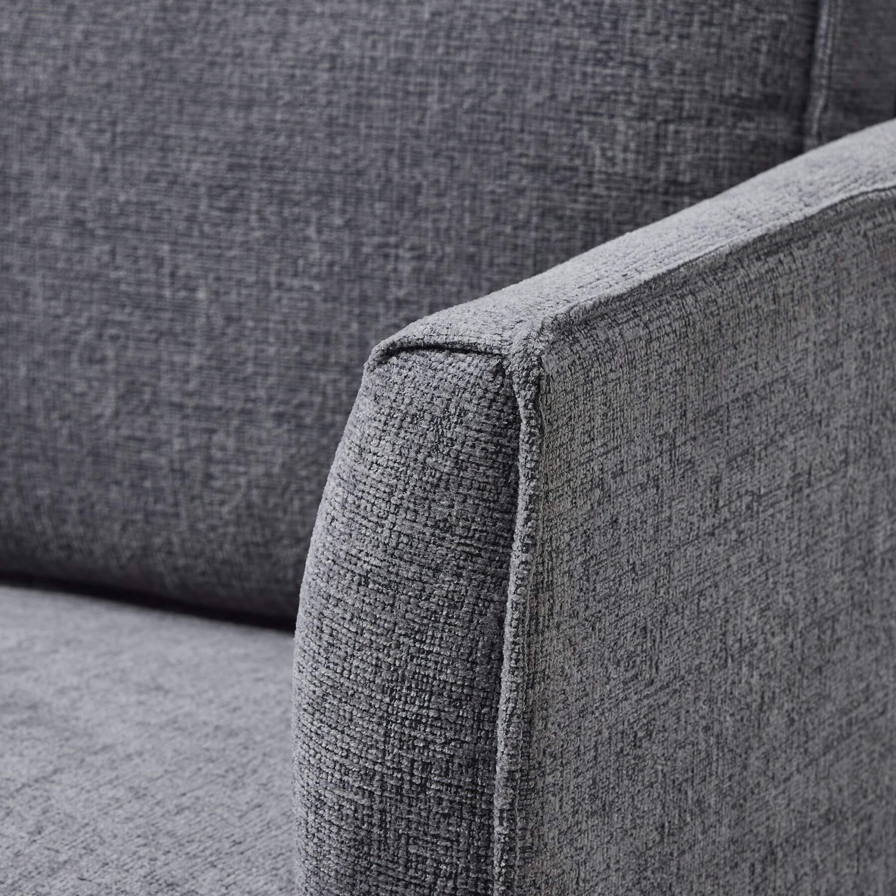 Grey fabric armchair with curved arms, modern design, and plush upholstery for stylish living room seating by Sostter at brixbailey.com