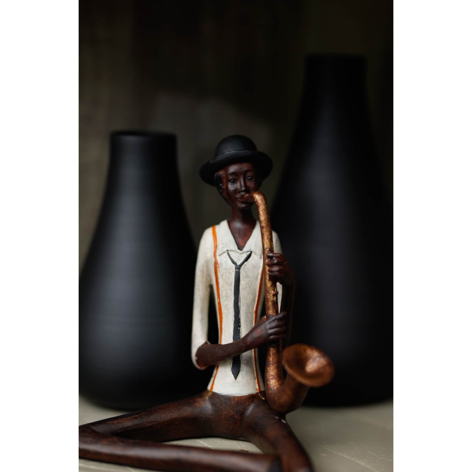 Handcrafted resin jazz saxophonist figurine in warm brown with hanging leg for shelf display by Sostter at brixbailey.com