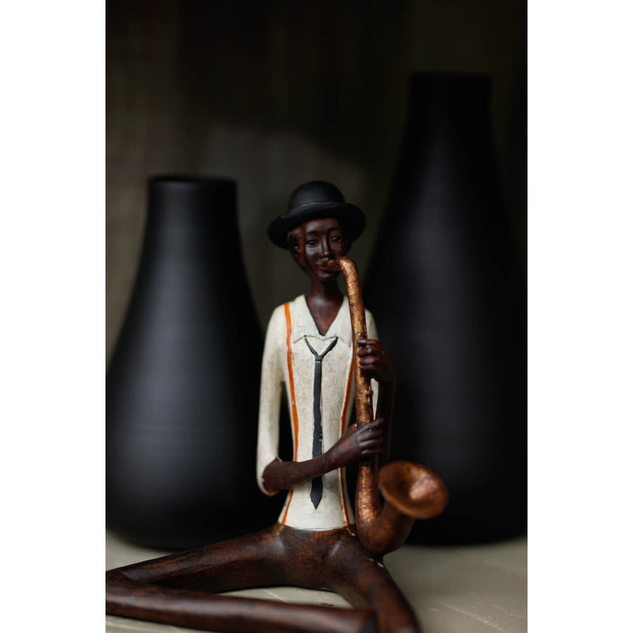 Handcrafted resin jazz saxophonist figurine in warm brown with hanging leg for shelf display by Sostter at brixbailey.com