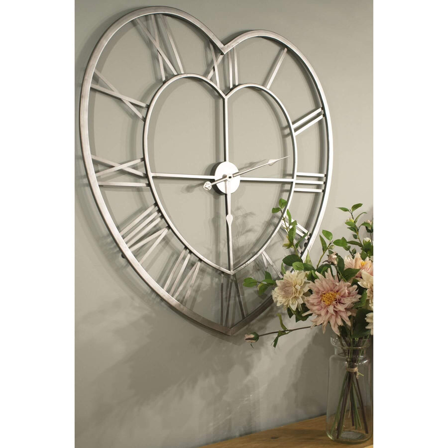 Heart-shaped skeleton wall clock in polished silver with roman numerals, minimalist metal design, 89cm diameter by Hill Interiors at brixbailey.com
