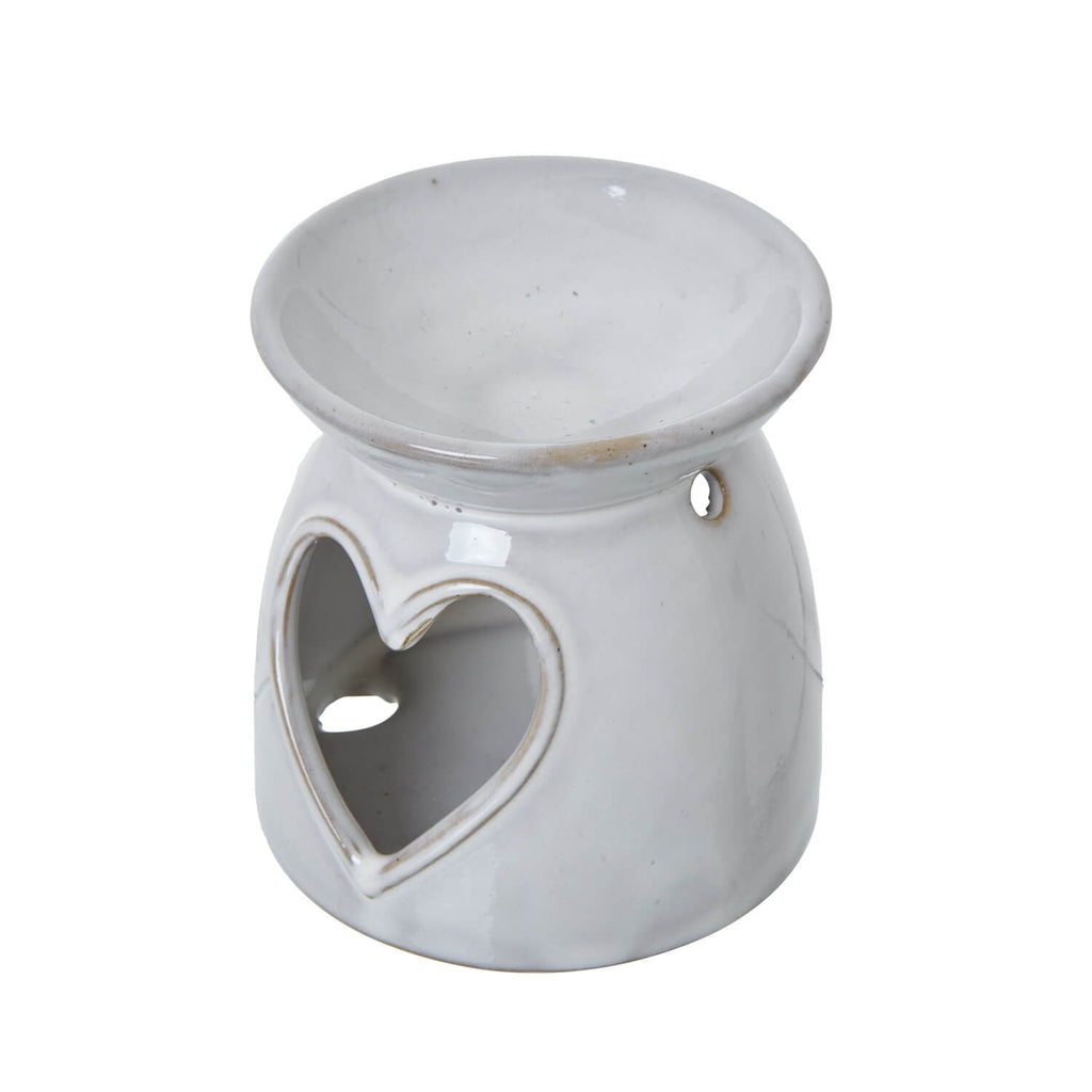 White ceramic tealight holder with heart cut-outs, casting delicate light patterns for cozy ambiance by sostter at brixbailey.com