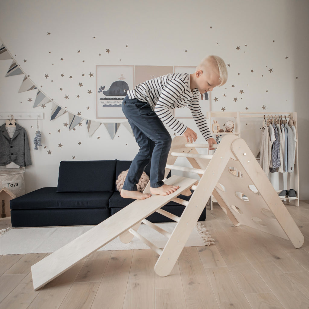 boy using a handmade climbing frame in wood wearing  a striped top from Brix + Bailey. 