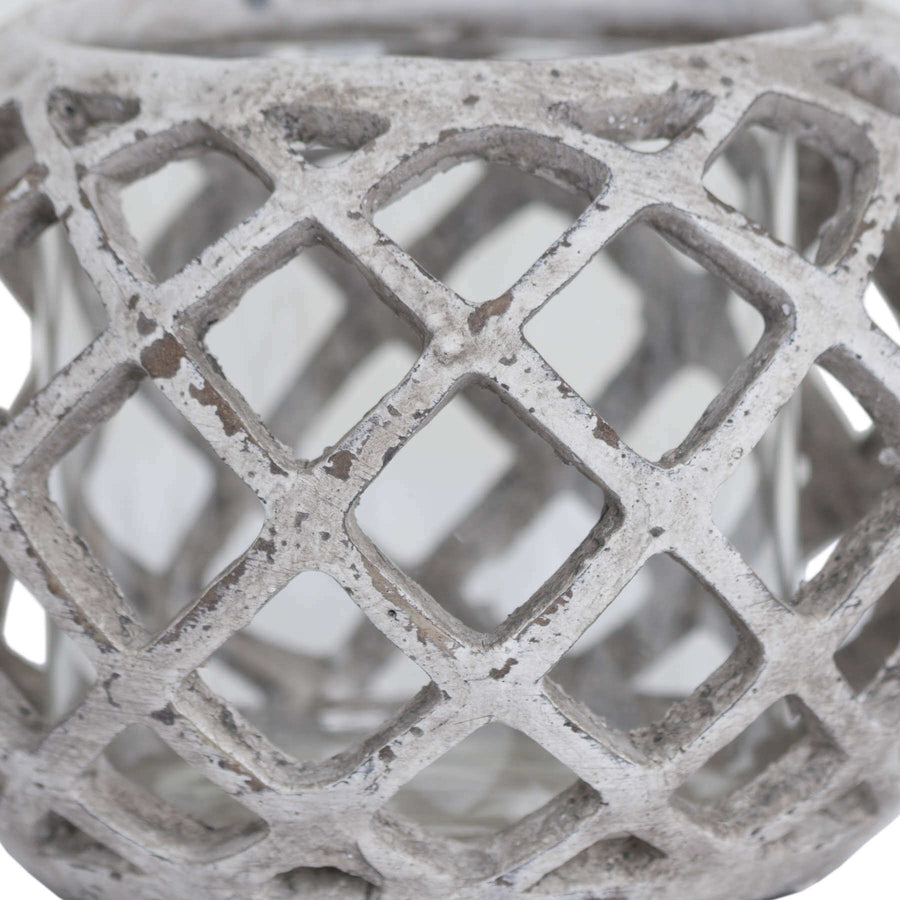 Handcrafted ceramic hurricane lantern with geometric lattice design, casting mesmerizing light patterns in neutral stone finish. by Sostter at brixbailey.com