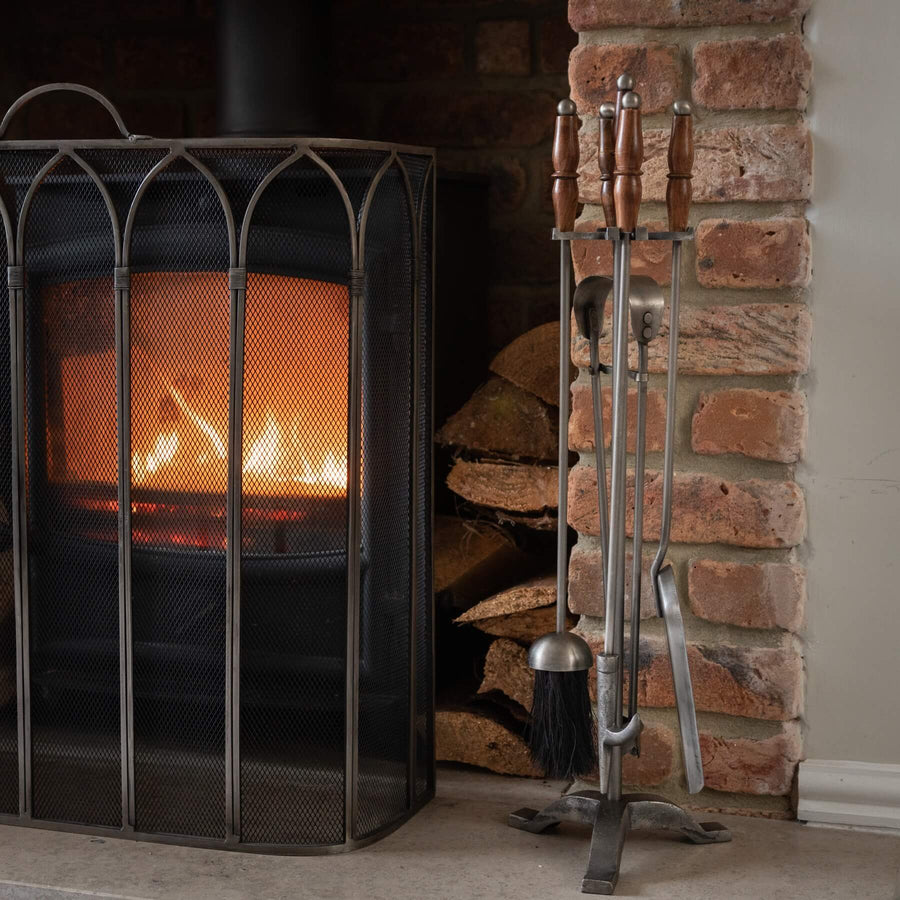Handcrafted antique pewter fireplace set with wood handles, earthy brown tones, and intricate metalwork. by Sostter at brixbailey.com