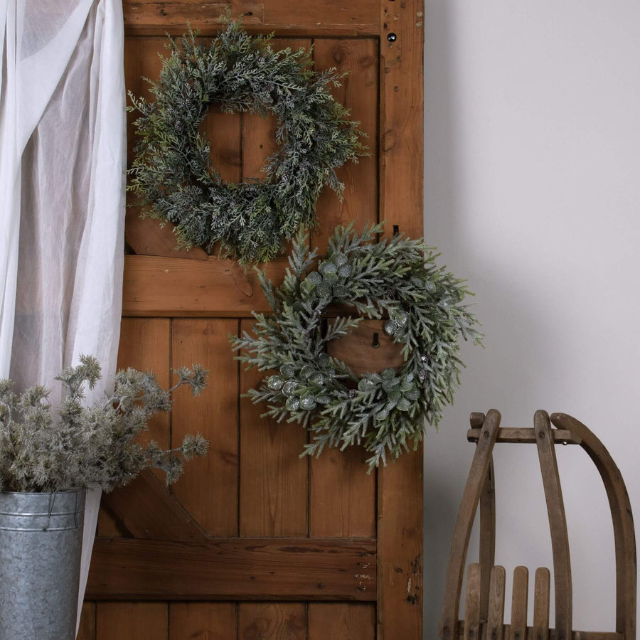 Frosted pine wreath with lifelike frost effect, pinecones, and silver-green accents for winter home decor. by Sostter at brixbailey.com