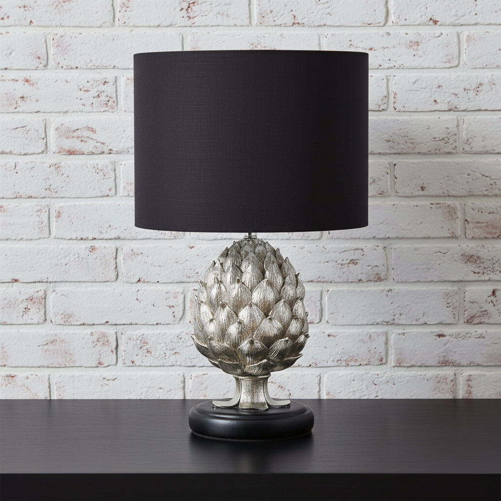 Decorative table lamp with a black shade and silver artichoke base on a white background on sostter.com