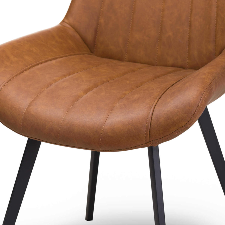Modern Scandinavian dining chair in warm brown faux leather with black metal legs, minimalist design. by Sostter at brixbailey.com
