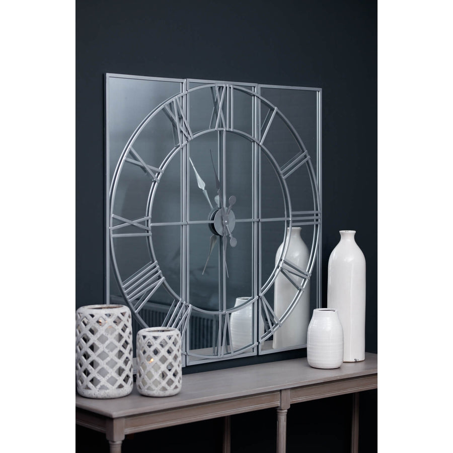 Celina mirrored wall clock with silver metal frame, modern skeleton design, and reflective glass surface, 112cm diameter by Sostter at brixbailey.com