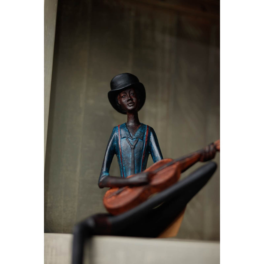 Handcrafted brown resin jazz guitarist sculpture with hanging leg, part of Sitting Jazz Band series. by Sostter at brixbailey.com