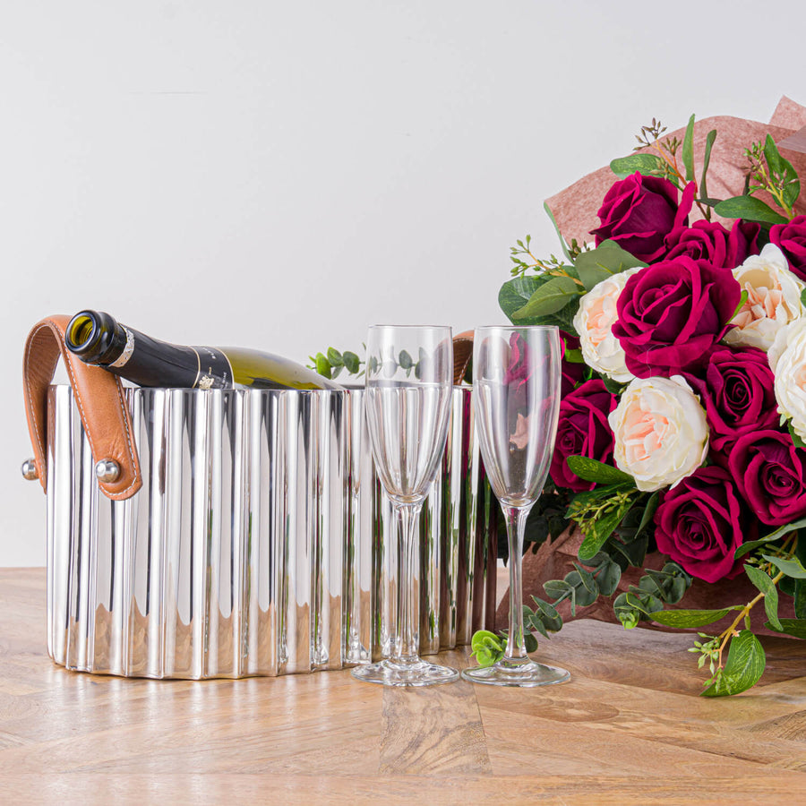 Silver champagne cooler with fluted metal body, leather handles, and mirror-polished finish for elegant entertaining by Sostter at brixbailey.com