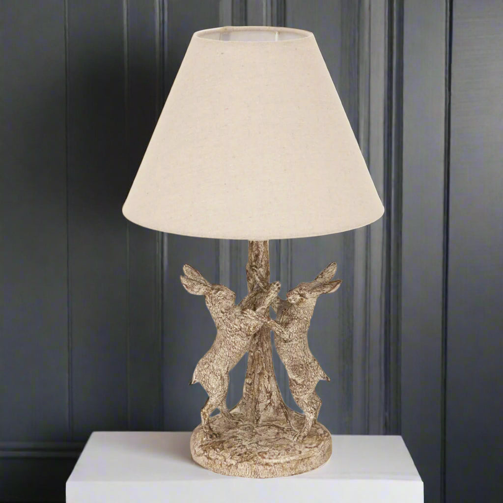 Stonewashed grey-brown Marching Hares table lamp with sculpted resin hares and natural linen shade by Sostter at brixbailey.com