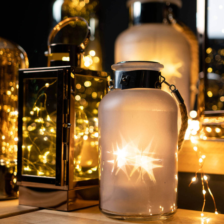 Frosted grey glass lantern with rope handle, glowing LED lights creating starlight effect, perfect for indoor or outdoor decor. by Sostter at brixbailey.com