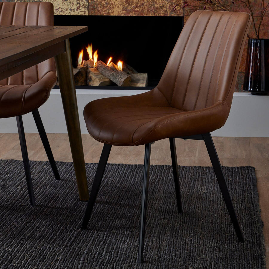 Modern Scandinavian dining chair in warm brown faux leather with black metal legs, minimalist design. by Sostter at brixbailey.com