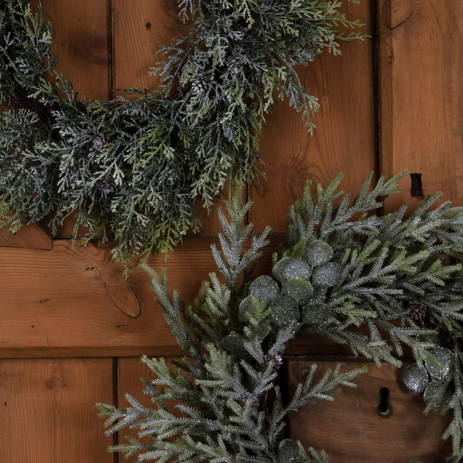 Frosted pine wreath with realistic frost effect, pinecones, and silver-green accents for winter home decor. by Sostter at brixbailey.com