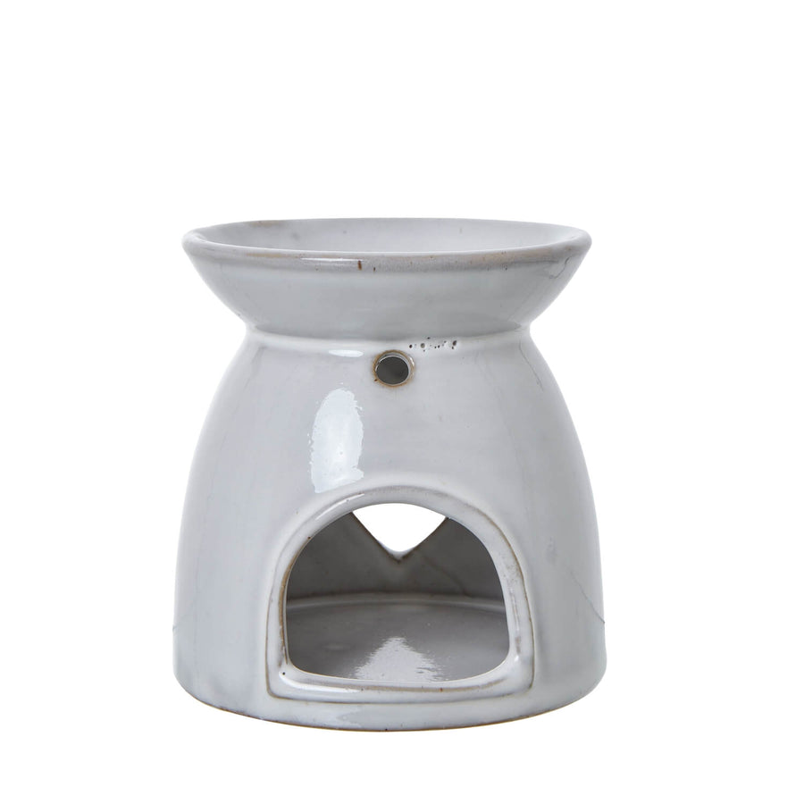 White ceramic heart-shaped tealight holder with intricate cut-out design casting warm light patterns by Sostter at brixbailey.com