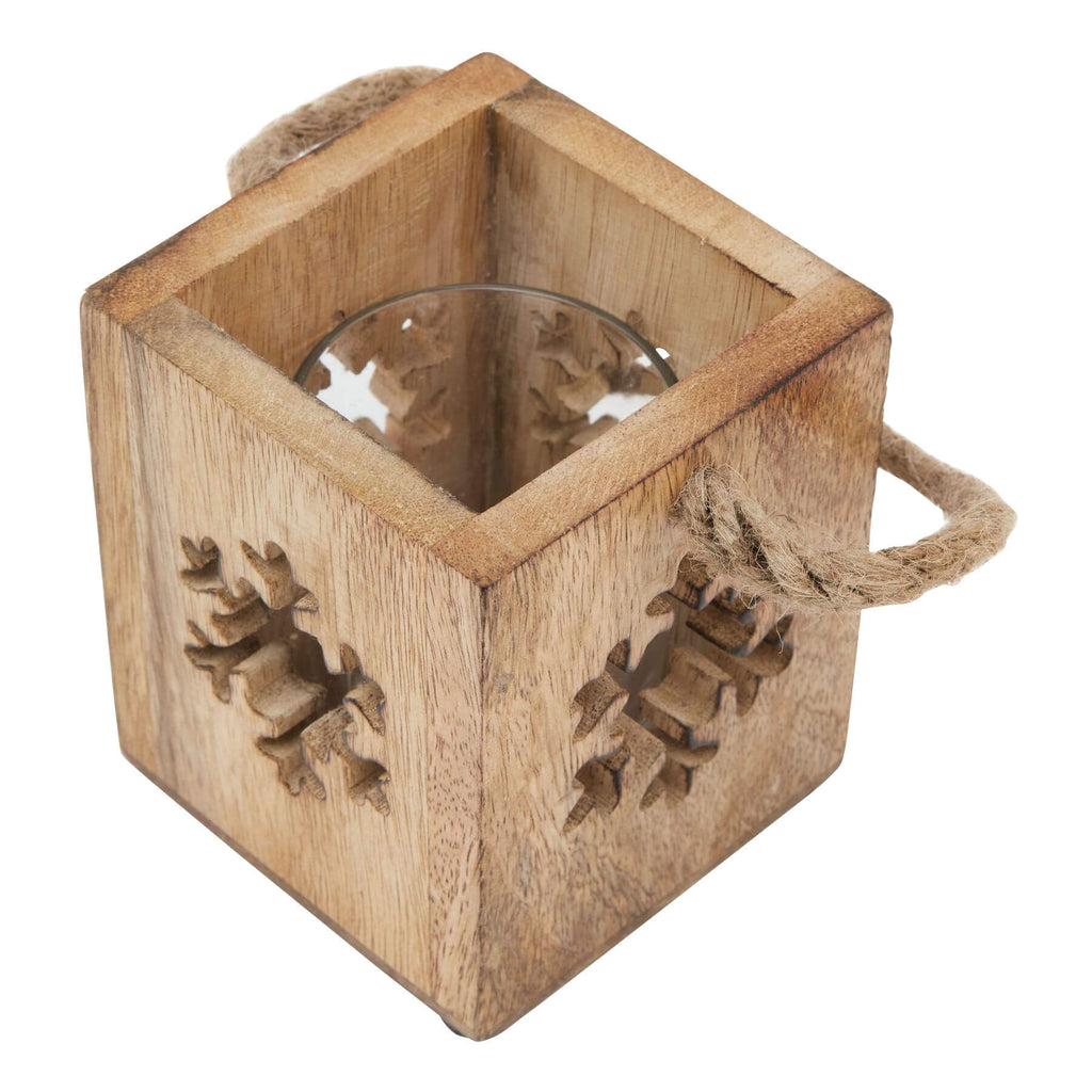 Handcrafted wooden snowflake tealight holder with glass accents, casting warm winter shadows in rustic brown tones. by RoomLondon at brixbailey.com