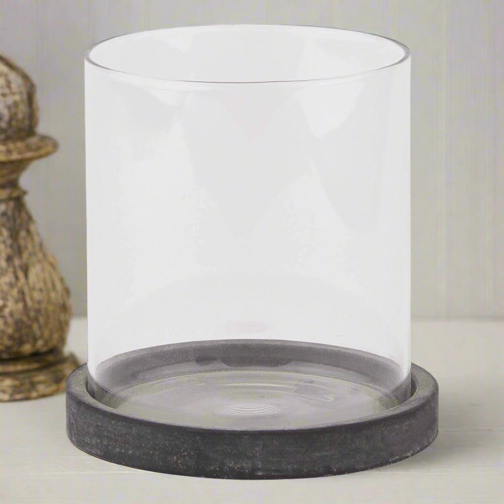 Grey ceramic hurricane lantern with glass panels, Mediterranean coastal style, casting ambient light patterns for indoor or outdoor decor. by Sostter at brixbailey.com