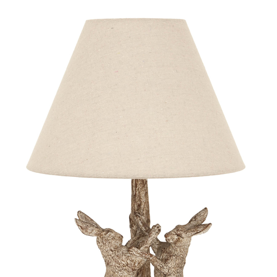 Stonewashed resin table lamp with marching hares design, natural linen shade, earthy brown and grey tones. by Sostter at brixbailey.com