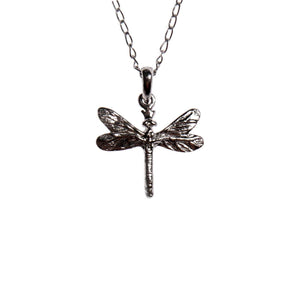 confident close-up of a dark dragonfly pendant on a silver chain, gemstones glinting with bold strength