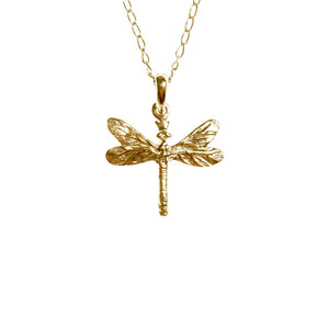 bold close-up of a captivating gold dragonfly pendant on a model