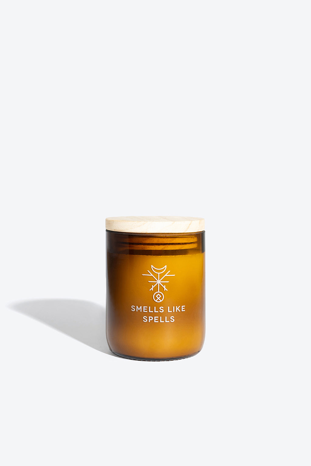 softly lit kvasir scented candle in amber glass, casting a warm, tranquil glow on a wooden surface