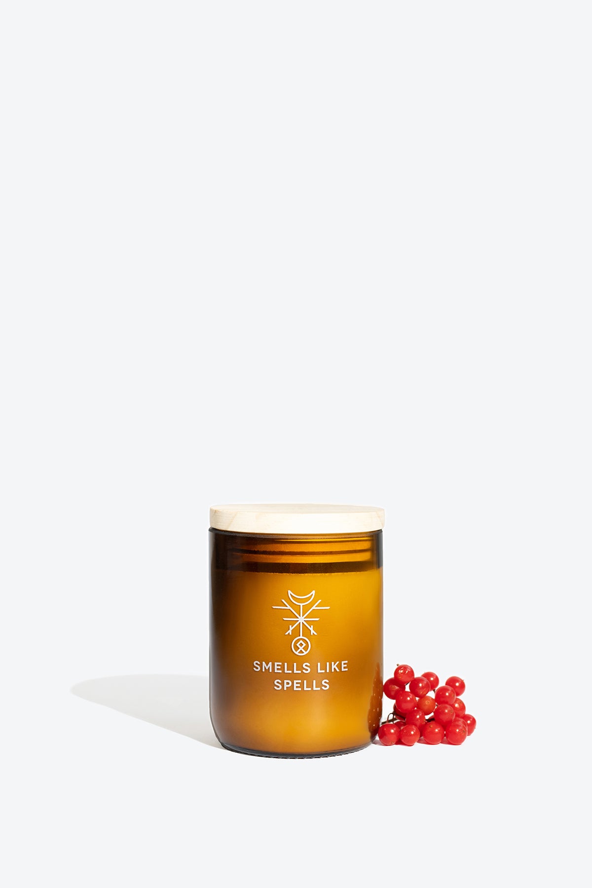 elegant bragi scented candle in amber glass, glowing with a warm wooden wick on a sophisticated marble surface