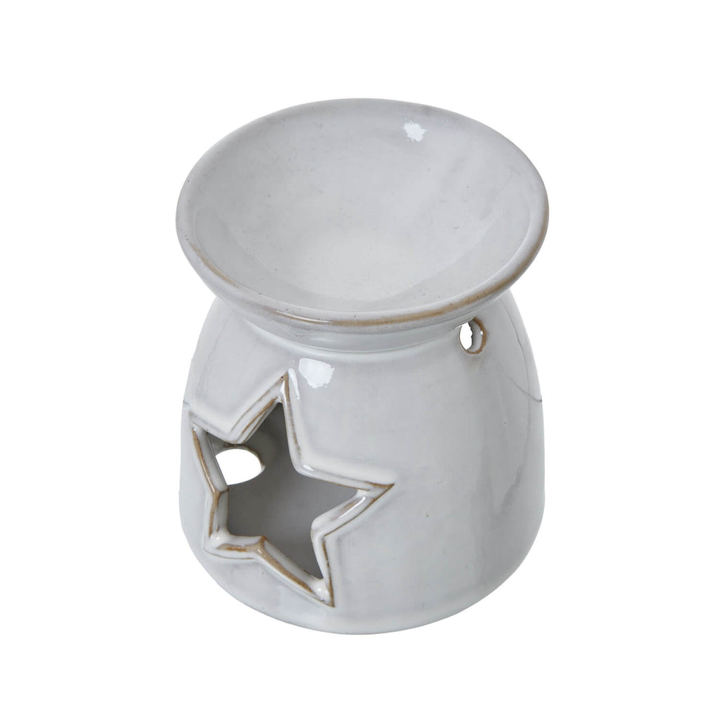 White ceramic tealight holder with star cut-outs casting intricate shadow patterns, perfect for wax melts or candles by sostter at brixbailey.com