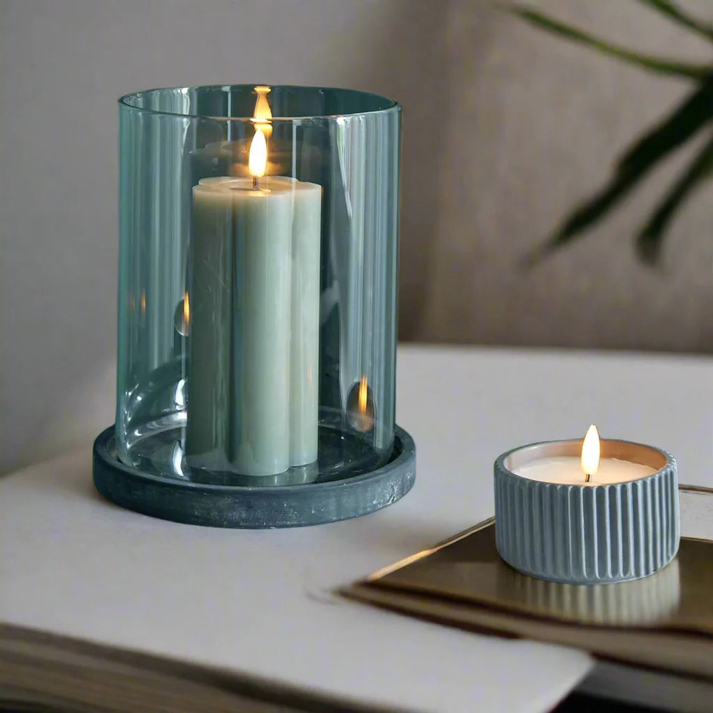 Grey ceramic hurricane lantern with glass panels, creating warm candlelit ambiance for indoor or outdoor decor. by Sostter at brixbailey.com