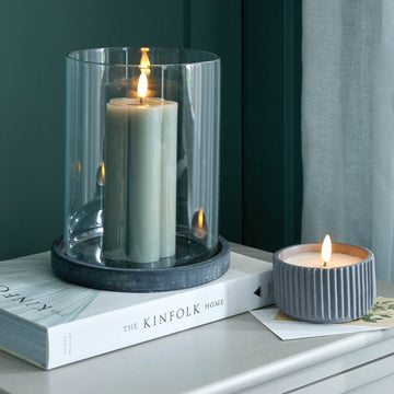 Grey ceramic hurricane lantern with glass panels, creating warm candlelit ambiance for indoor or outdoor decor. by Hill Interiors at brixbailey.com