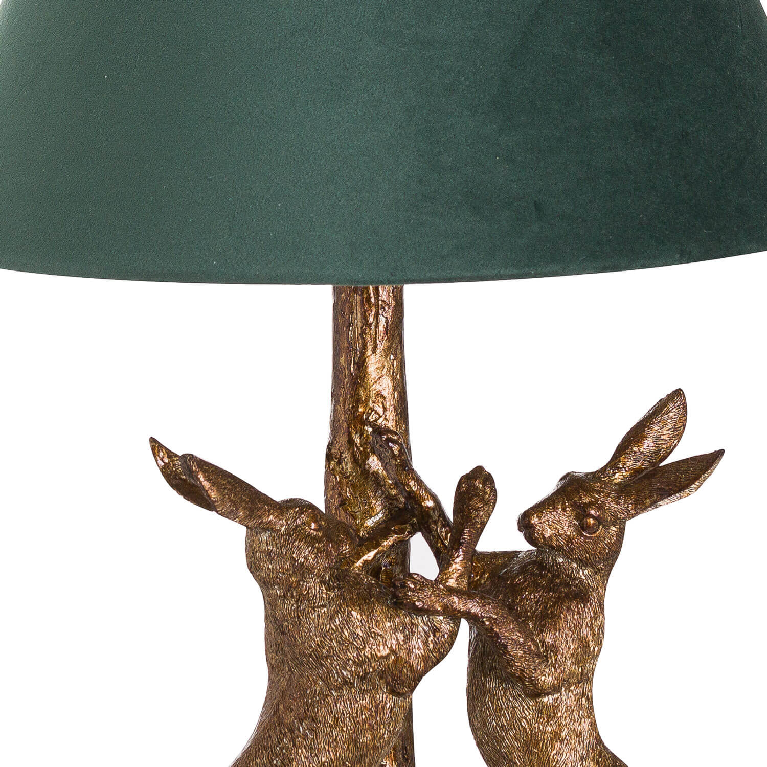 Antique gold marching hare lamp with green velvet shade, handcrafted resin sculpture casting warm ambient glow when lit. by Sostter at brixbailey.com