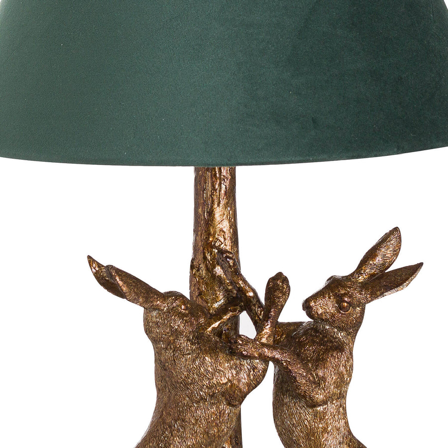 Antique gold marching hare lamp with green velvet shade, handcrafted resin sculpture casting warm ambient glow when lit. by Sostter at brixbailey.com