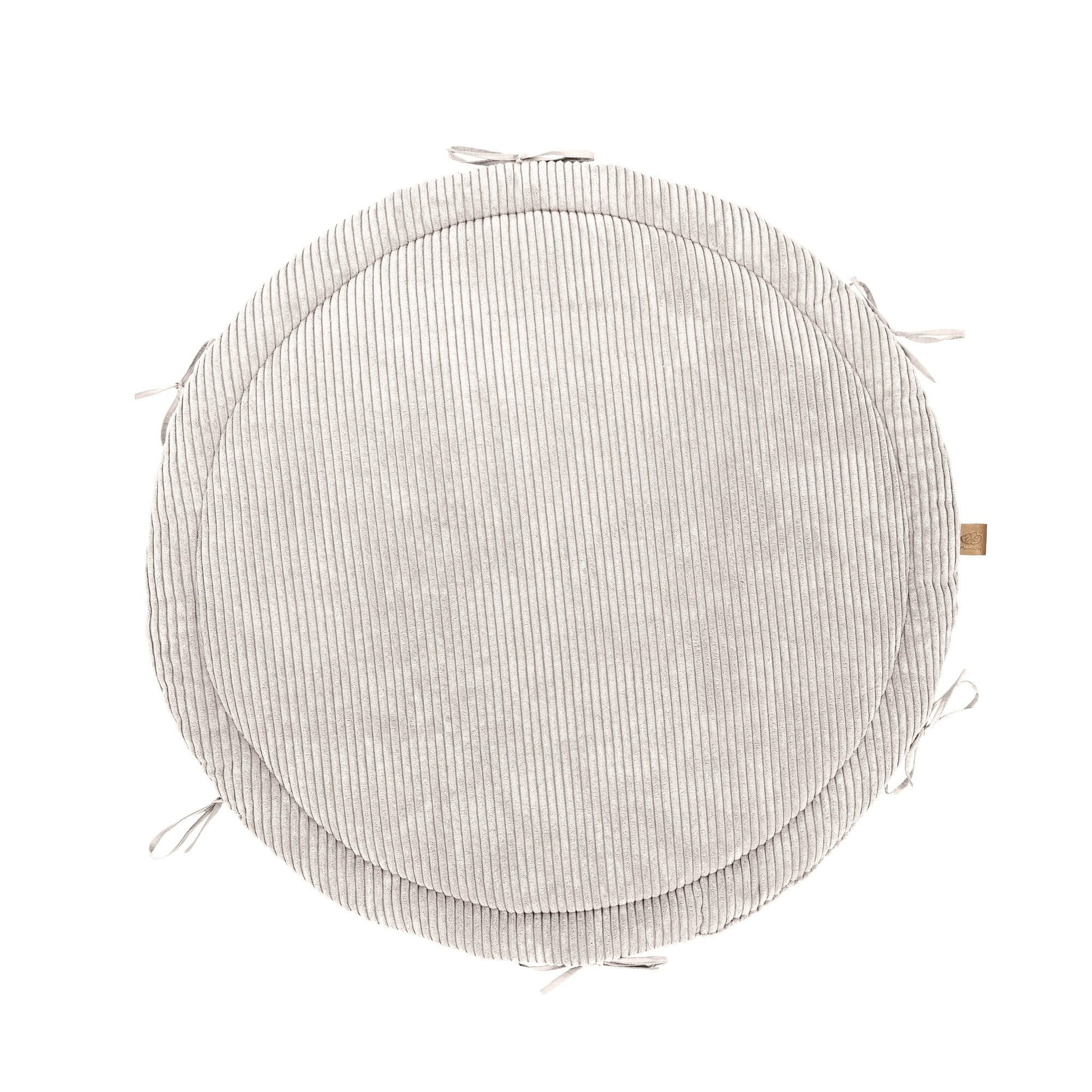 a soft vanilla baby nest with a plush braided bumper on a cozy nursery rug