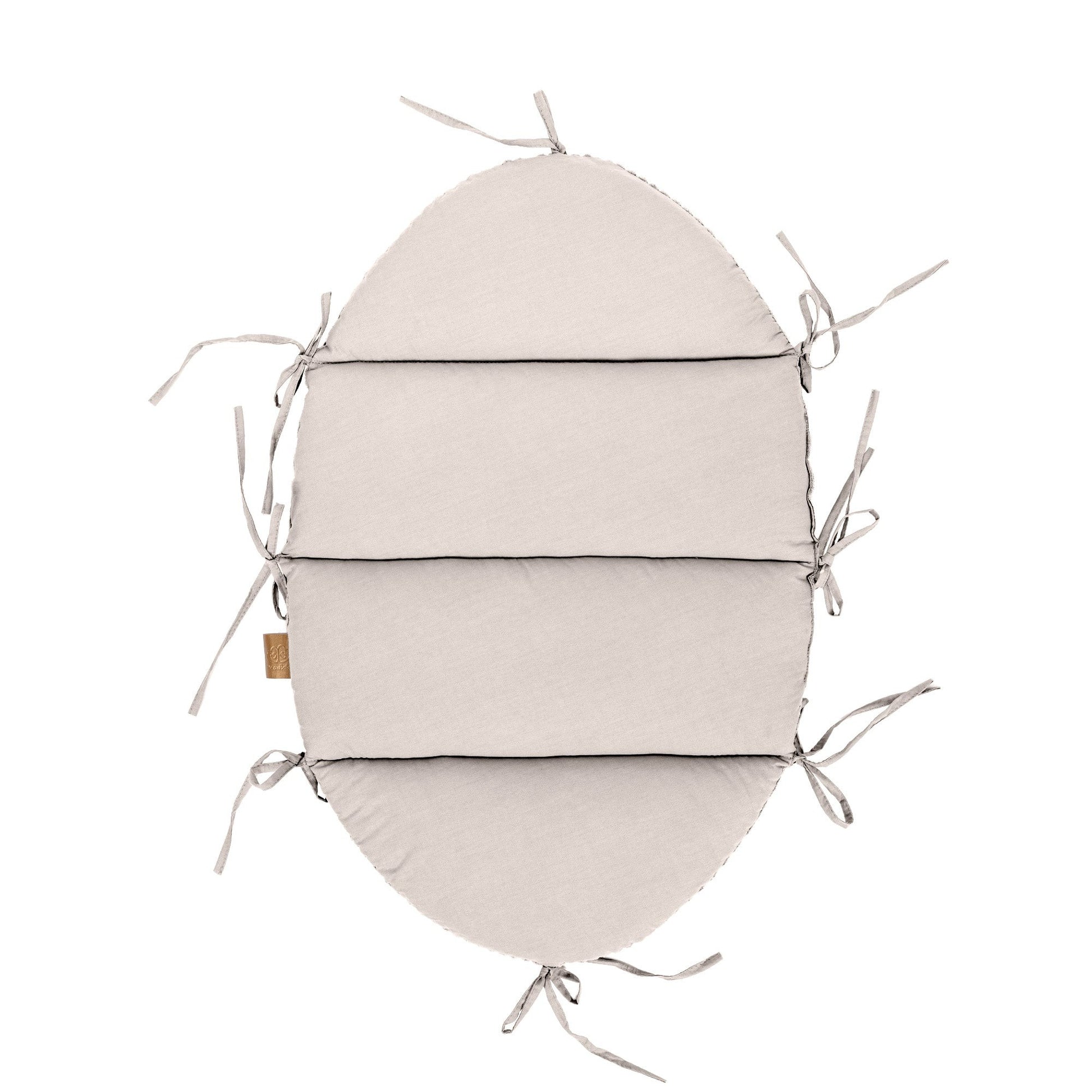 soft ecru baby nest with a long braided bumper in warm morning light