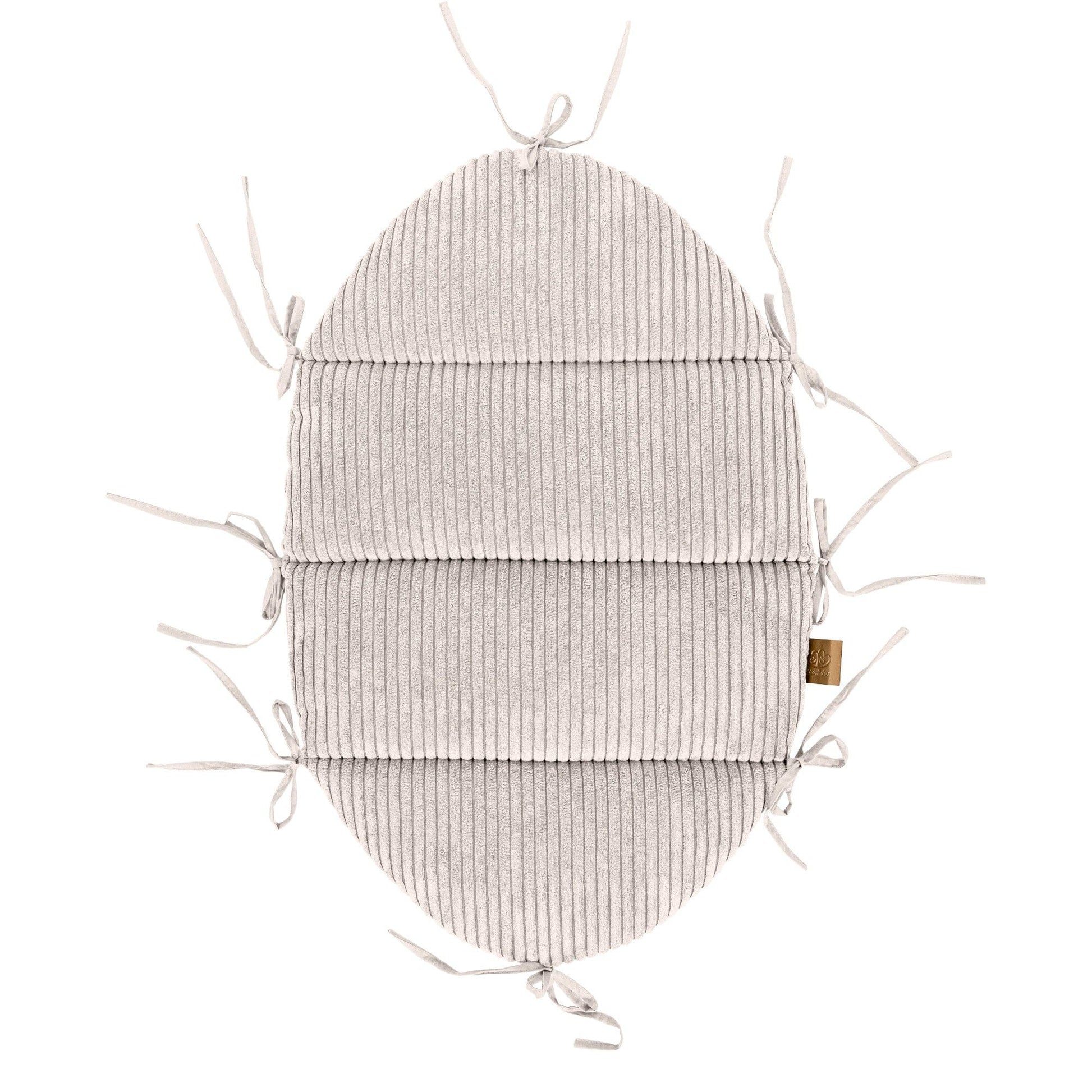 elegant ecru baby nest with long braided bumper on a neutral linen backdrop