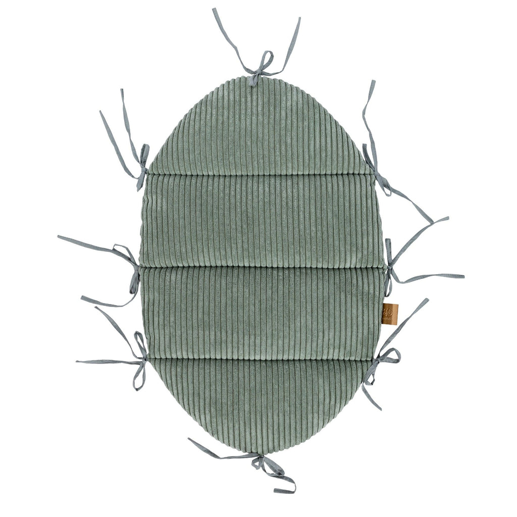 soft olive green baby nest with a cozy braided bumper in warm morning light