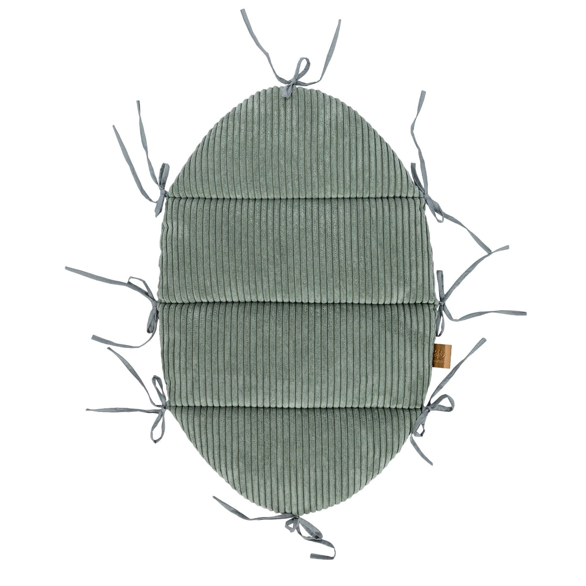 soft olive green baby nest with a cozy braided bumper in warm morning light