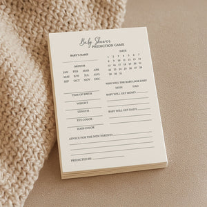 a soft, close-up shot of a creamy a6 baby shower prediction card on a cozy knitted blanket