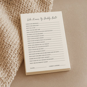 a soft-lit close-up of the who knows daddy best game cards on a cozy knitted blanket