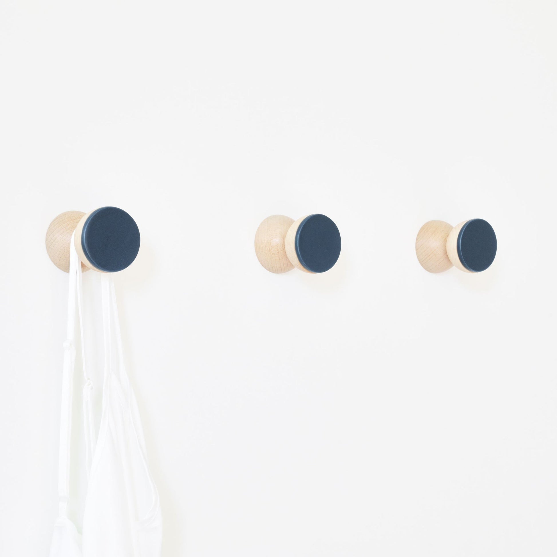 bold dark blue ceramic wall hook on a minimalist concrete background