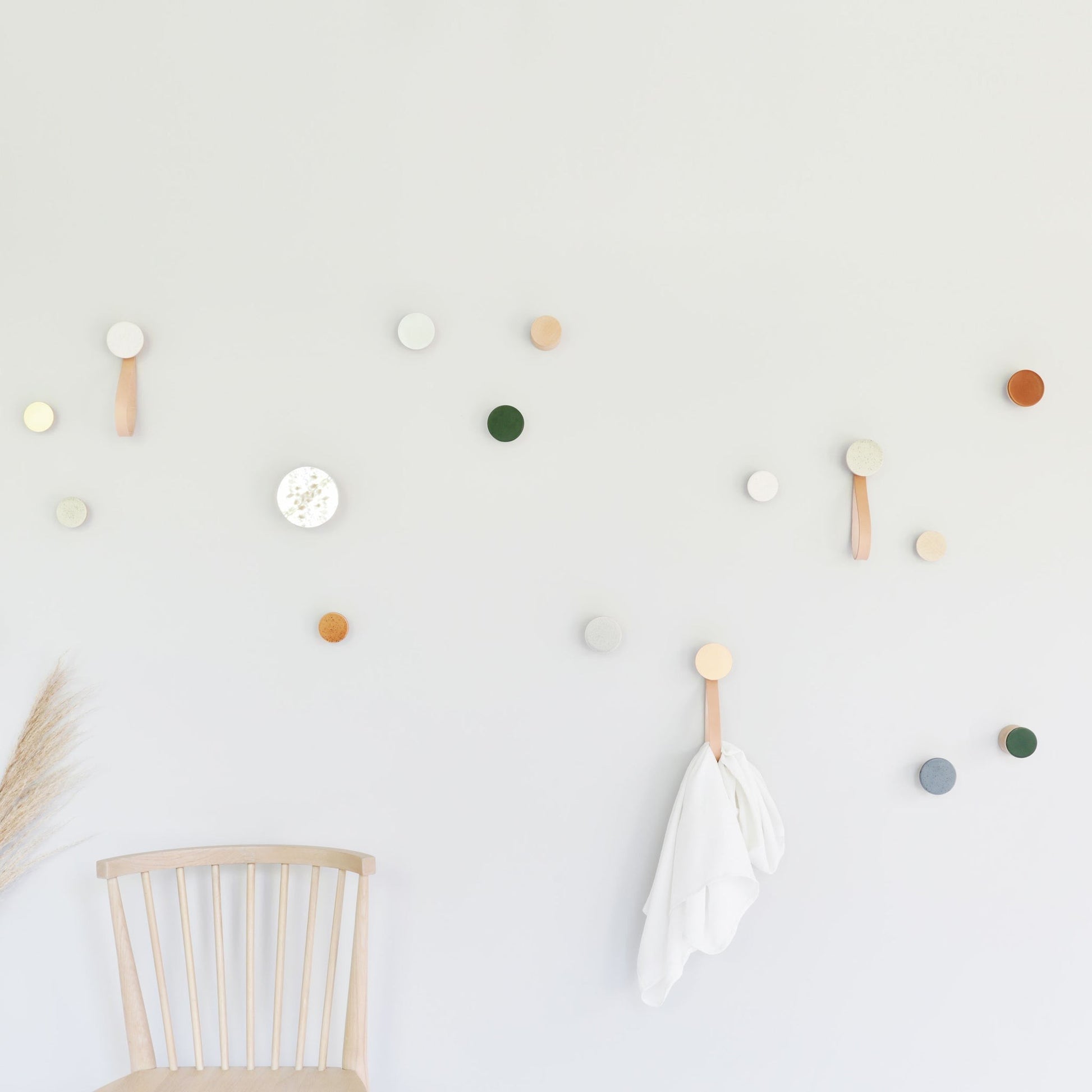 playful dark terracotta ceramic hook with warm wood on a bright garden wall
