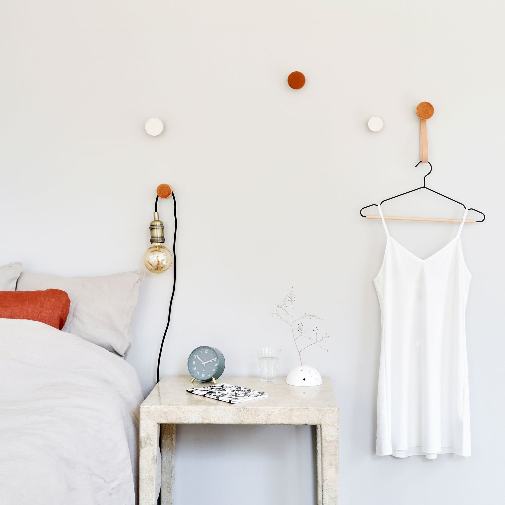 elegant dark terracotta ceramic wall hook on beech wood in soft morning light