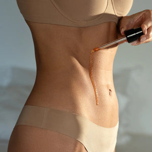 a soft golden glow of mellow pitch body oil being gently poured onto skin