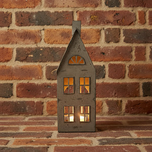 a bold, tall metal tealight house casting dramatic shadows from a low-angle shot brix and bailey