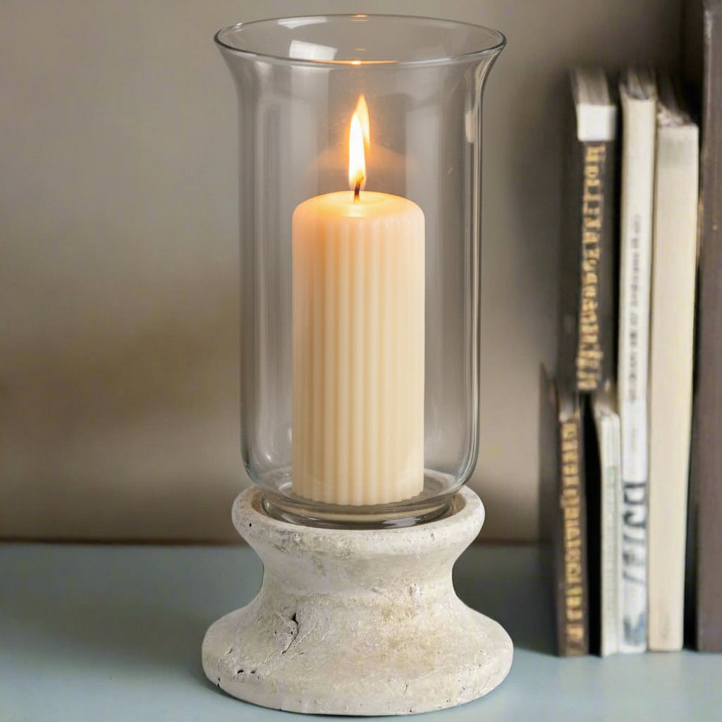 Handcrafted cream hurricane lantern with stone-effect base and antiqued patina, casting warm LED candlelight glow. by RoomLondon at brixbailey.com