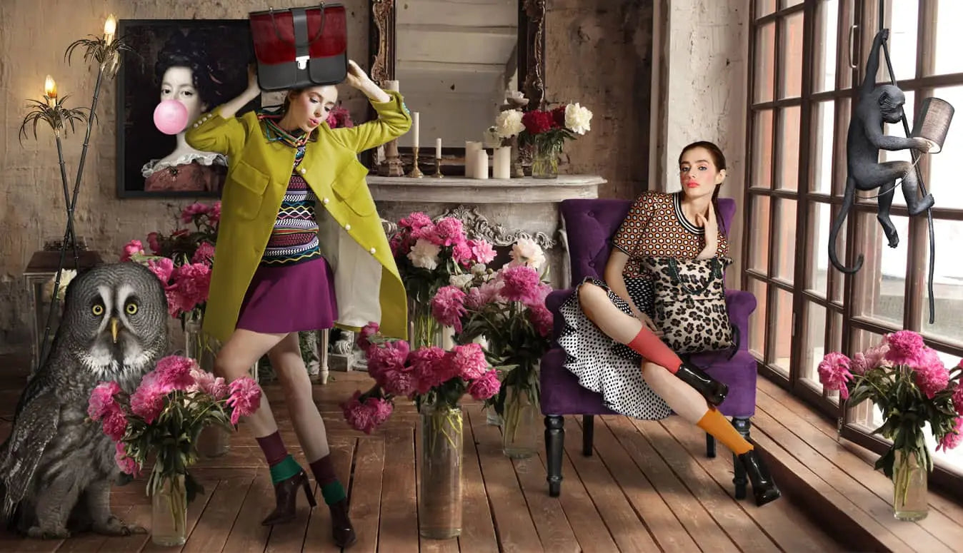 Two women in a stylish room with flowers, furniture, and decorative items.